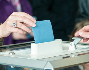 Une personne en train de déposer un bulletin de vote dans une urne