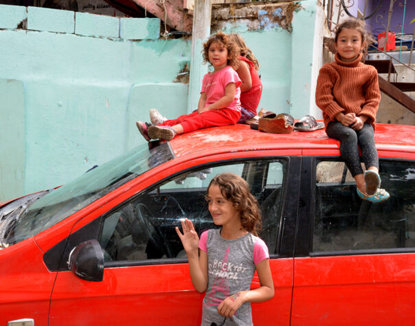 Des fillettes palestiniennes de moins de 5 ans assises sur une voiture rouge. Une autre, 9 ans environ, devant la voiture.