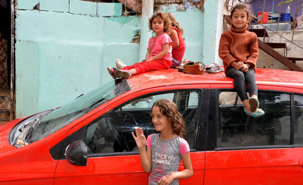 Des fillettes palestiniennes de moins de 5 ans assises sur une voiture rouge. Une autre, 9 ans environ, devant la voiture.