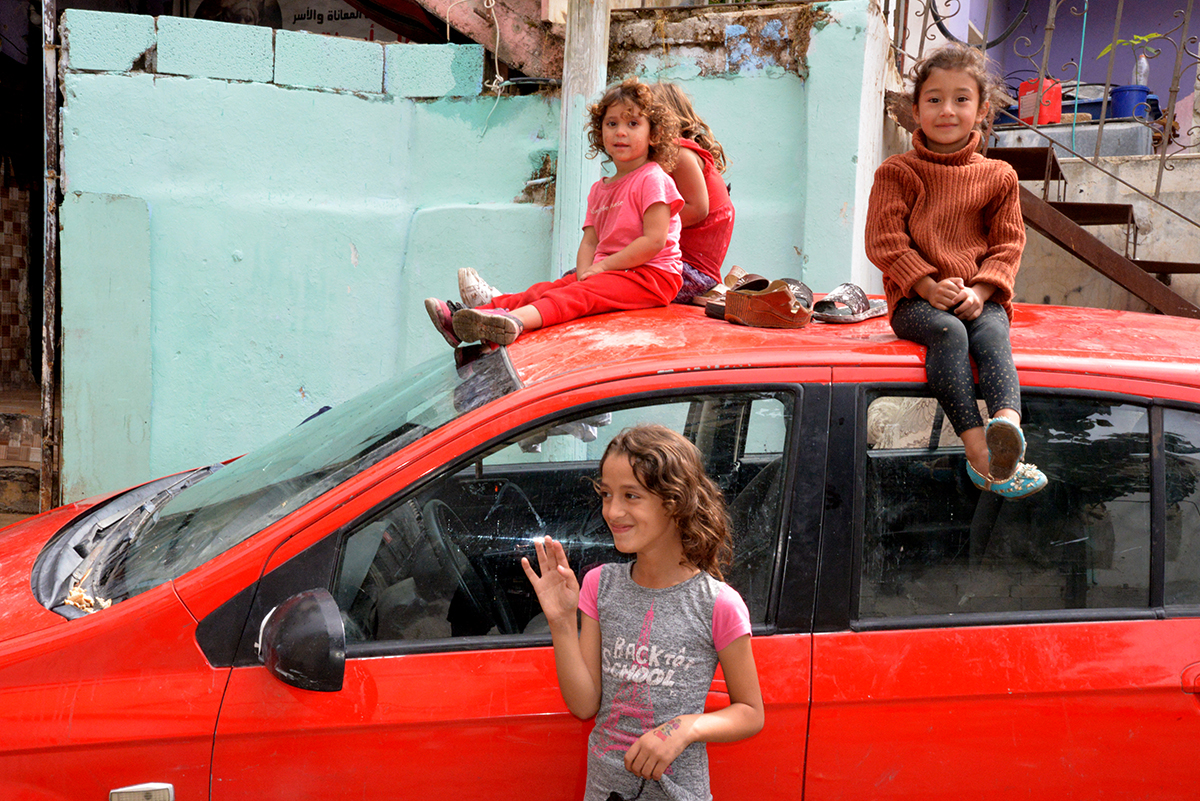 Des fillettes palestiniennes de moins de 5 ans assises sur une voiture rouge. Une autre, 9 ans environ, devant la voiture.